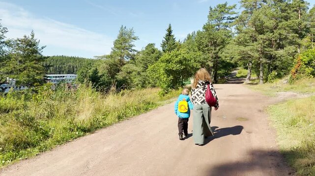 A woman and child walk together along a sunny path in Valaam, Lake Ladoga. This joyful journey brings a calm, happy feeling of peaceful family harmony.