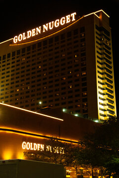  Illuminated Golden Nugget hotel and casino facade in Atlantic City at night, glowing neon signage and warm exterior lighting highlighting the architecture and bustling urban nightlife atmosphere