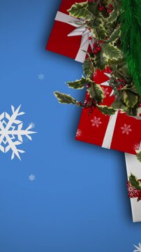 Snowflakes falling over christmas wreath decoration and gifts against blue background