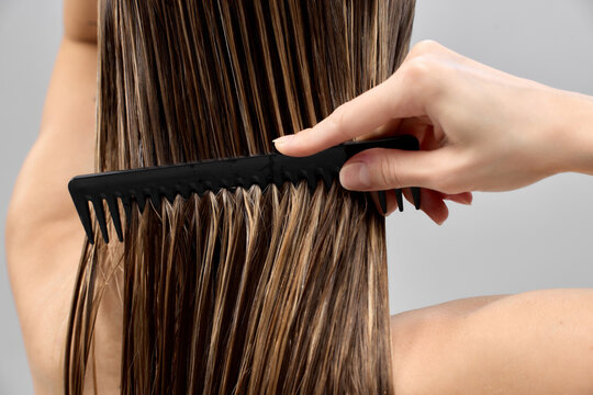 Gentle detangling motion separates damp hair strands with wide tooth comb. Concept of breakage prevention, conditioner results, softness and easy styling.