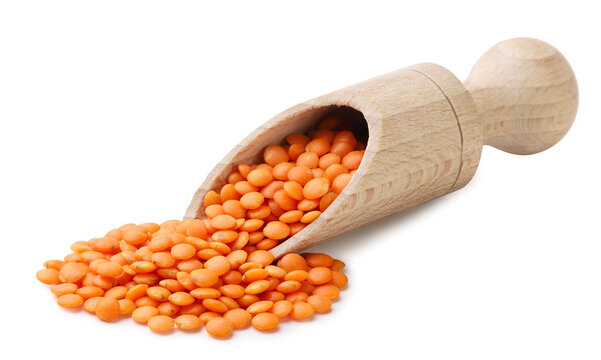 Red lentils pouring from a wooden scoop on a white. Isolated