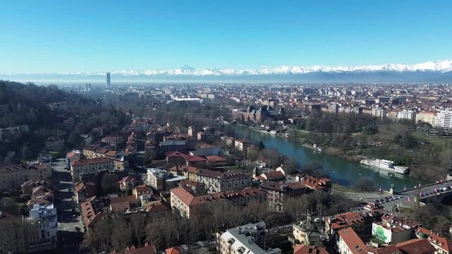 Panoramic aerial drone shot of Turin cityscape with Po River, Valentino Park and majestic Monviso mountain peak in snow, Italy