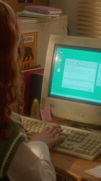 Vertical shot of teenager typing on retro computer keyboard and chatting online from over-shoulder view. Video is perfect for nostalgic marketing campaigns or tech history projects