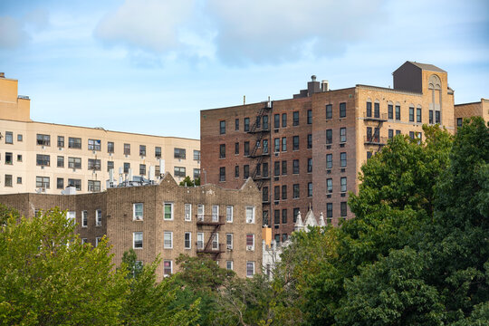 Traditional residential housing blocks and brick apartment buildings rise above green trees in The Bronx neighborhood of New York.