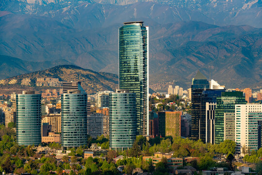 A scenic view of the modern glass towers at the Parque Titanium real estate development in Santiago, Chile, with the impressive Andes mountain range rising in the background.