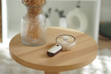 brown portable rechargeable mini handheld fan rests on a small wooden table © Towfiqu Barbhuiya 