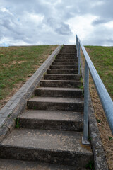 Fototapeta premium Staircase climbs through overcast weather, surrounded by green grass