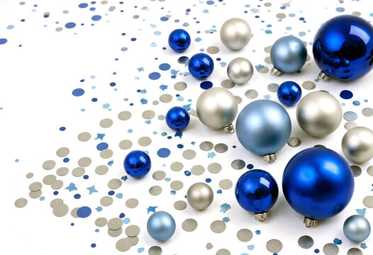 Festive collection of shiny blue and silver christmas ornaments with confetti scattered around them