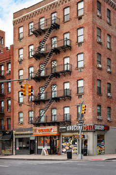 Urban street scene in the Manhattan Chelsea neighborhood New York with a traditional brick building classic metal fire escapes and a busy Deli and Grocery on the ground level.