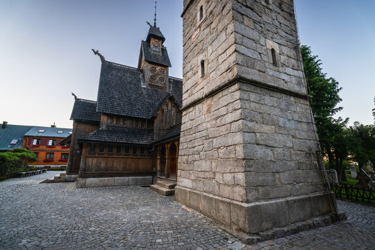 Karpacz, Poland - 29 July 2026: View of Wang Church, a historic wooden stave church with intricate carvings and a stone bell tower, set against a clear sky.