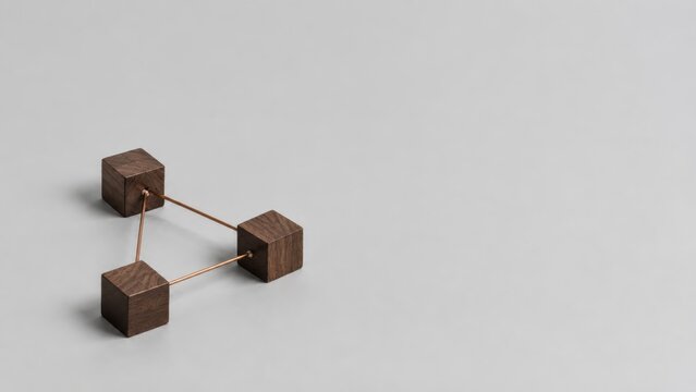 Three wooden cubes connected by thin rods, arranged on a smooth gray surface, forming a geometric structure with a minimalist aesthetic.