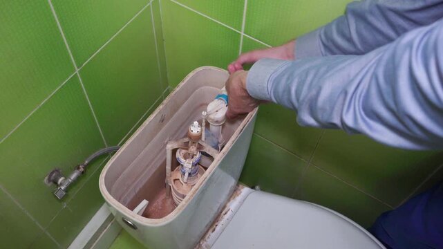 Fixing a water leak in the toilet, A man fixes a broken toilet cistern fitting