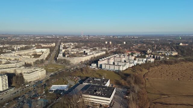 Aerial view of urban sprawl with residential buildings, roads, and distant industrial structures on a clear day.