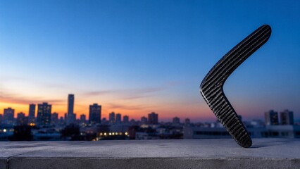 Naklejka premium Carbon fiber boomerang silhoueette against sunset city backdrop
