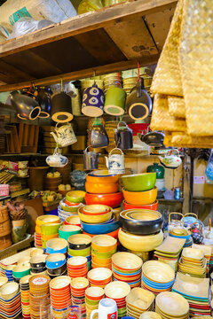 Phnom Penh, Cambodia - 13 February 2020: View of a vibrant market stall filled with colorful ceramic bowls, plates, and traditional teapots stacked on wooden shelves.