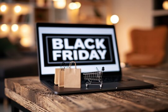 Laptop displaying a black friday sale with a miniature shopping cart and paper bags