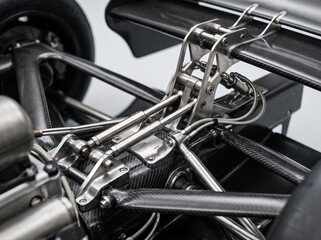 Naklejka premium detailed close up shot of carbon fiber and metal rear suspension and wing structure of a race car
