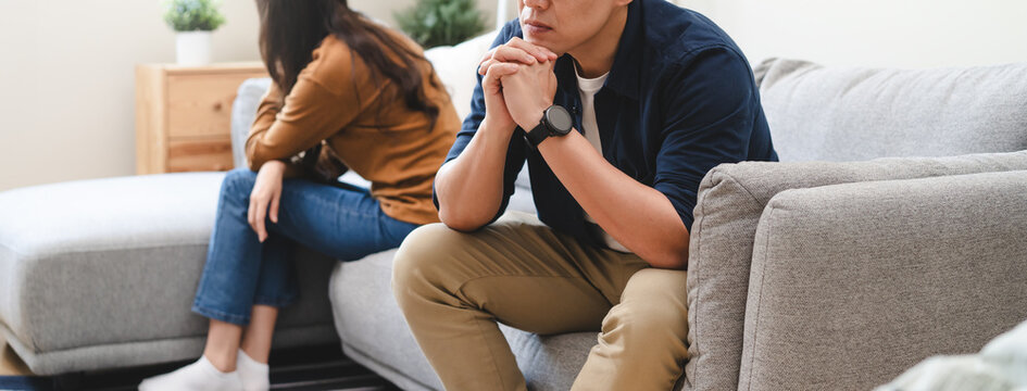 Family problem concept, Close-up hands of Asian wife sitting on sofa and husband sitting back to back in the living room at home have problems in a relationship and have an argument