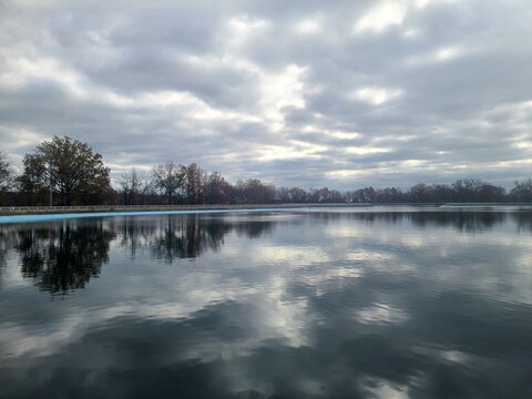 Calm reservoir with mirrored cloud reflections under an overcast sky