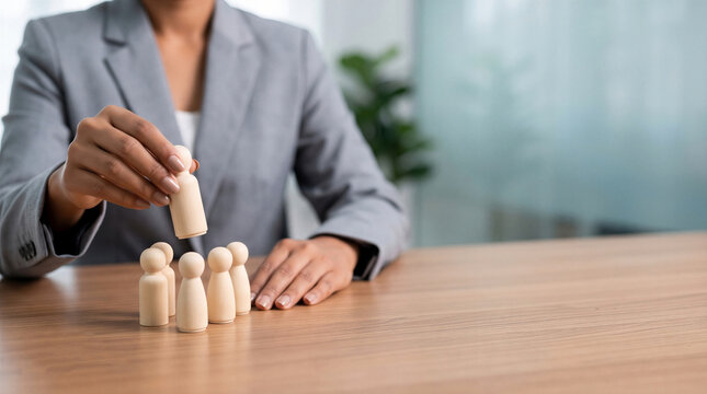 Businesswoman choosing a wooden figure from a group. Concept of recruitment, leadership, human resources, and talent selection
