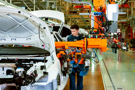 Automotive Assembly Line Worker Collaborating with Industrial Robot in Smart Car Factory