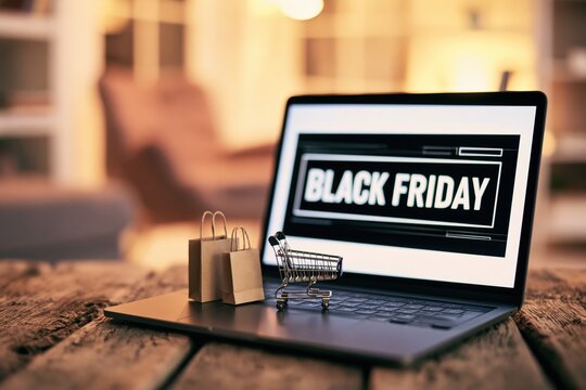 Laptop displaying a black friday sale with a miniature shopping cart and paper bags