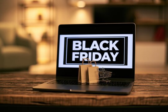 Laptop displaying a black friday sale with a miniature shopping cart and paper bags