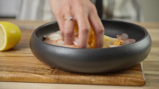 Marinating Fresh Prawns with Turmeric, Salt, and Fresh Squeezed Lemon. Indian hands mix ingredients with Argentinian red shrimp.