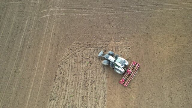 Overhead white tractor turning on freshly harrowed brown soil