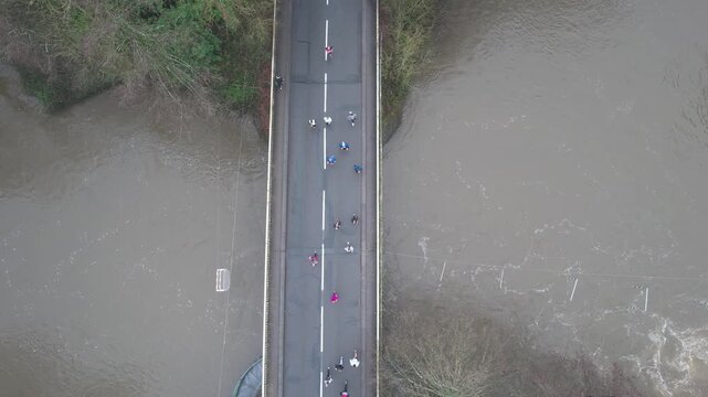 Nadir view of scattered runners crossing a flooded river bridge