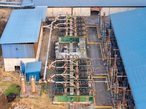 Aerial view of an industrial facility featuring blue-roofed buildings, complex piping networks, and machinery in Surakarta, Central Java, Indonesia.