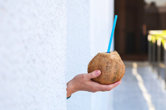 Female hand holding fresh coconut, exotic tropical lifestyle and refreshing summer drink.