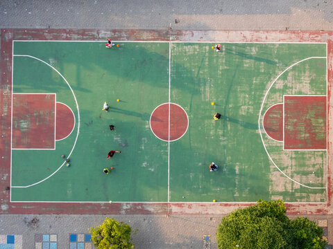 Aerial view of a basketball court with people playing on the green and red surface in Surakarta, Central Java, Indonesia.