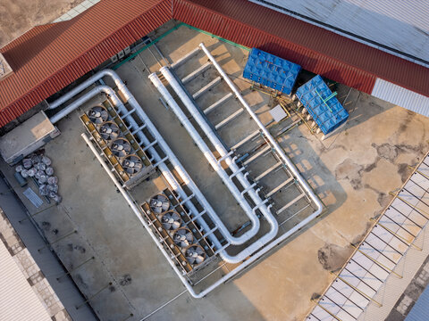 Aerial view of industrial HVAC cooling units and white piping systems installed on a flat rooftop in Surakarta, Central Java, Indonesia.