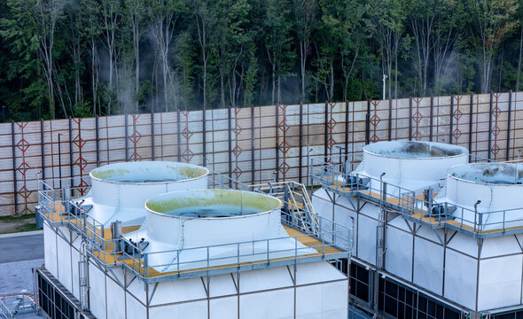 Aerial view of industrial cooling towers at a data center with steam rising and a wooden sound barrier wall in New Albany, Ohio, United States.