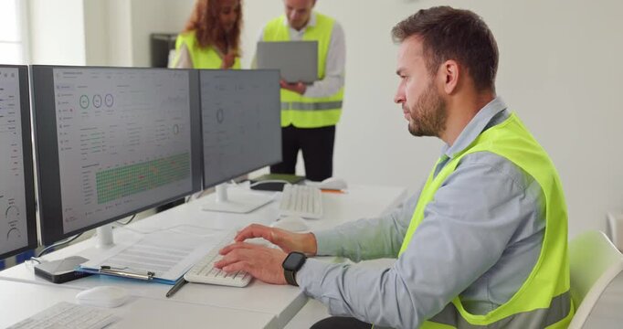 Engineers operators team in controlroom monitoring operations. Multiple screens show dashboards as staff ensure safety in an industrial site. Industrial safety with technology and analysis.