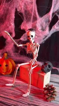 Spooky Halloween skeleton with jack o lantern, skulls and cobwebs