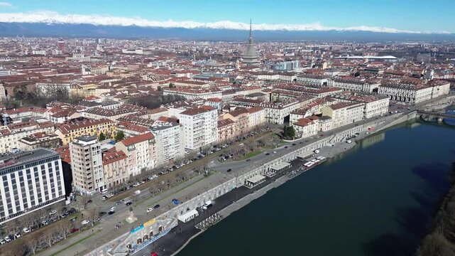 Wide high altitude drone view over Turin historic center, Po River bank and landmark Mole Antonelliana with Alpine snow mountains, Italy