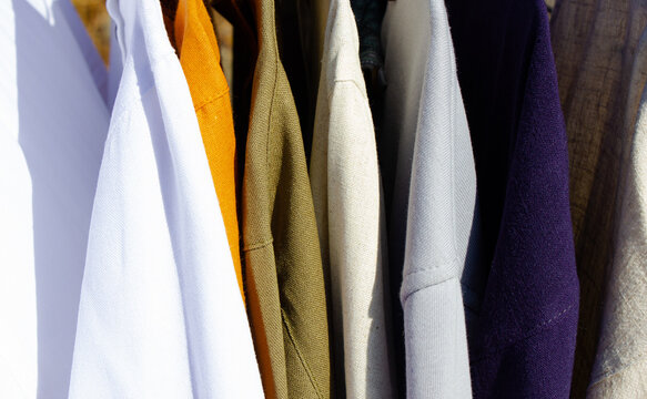 Clothing hanging on hangers. A selection of shirts and sweaters. Outerwear, a variety of options.
