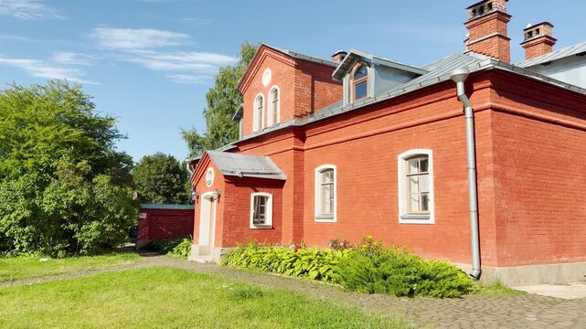 A red brick building stands under a bright blue sky in Valaam, Lake Ladoga. This historic skete structure inspires a peaceful, serene feeling of calm spiritual beauty.