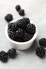 Ripe blackberries in bowl on light grey table, closeup © New Africa