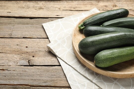 Fresh raw zucchinis on wooden table, closeup. Space for text