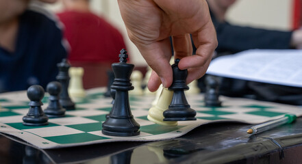 Hand moving a black chess piece during a game © Fabian Vargas