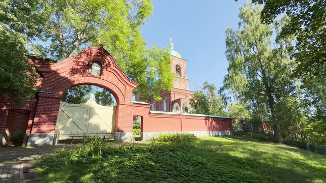A brick arch gate stands before a historic church on Valaam, Lake Ladoga. This beautiful religious landmark inspires a peaceful, serene, and majestic feeling.