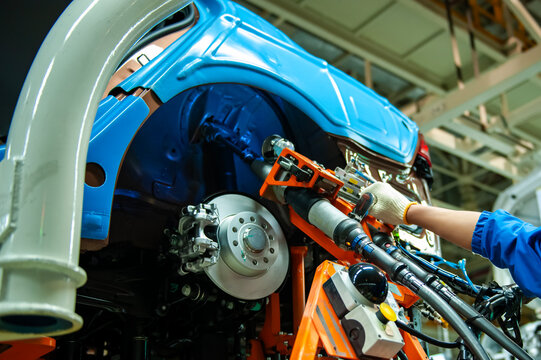 In an automotive assembly workshop, industrial pneumatic tools are used to install wheel bearings onto the vehicle body.