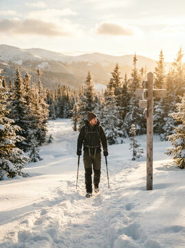 Man hiking with poles along a snowy forest path in warm winter sunlight
