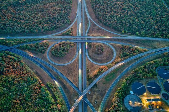 Aerial view of the highway interchange surrounded by dense forest and industrial facilities in Sausheim, Grand Est, France.