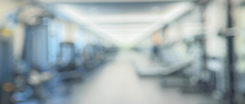A blurred view of a modern gym interior featuring various exercise equipment and a spacious layout, ideal for fitness enthusiasts and wellness-related projects.