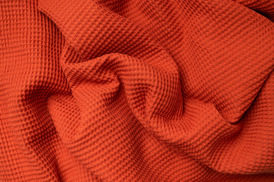 Fabric background. Close-up of natural cotton waffle fabric with soft folds. Cozy autumn background, macro shot of blanket, throw, or sewing material. Waffle towel texture.