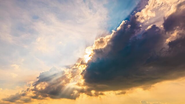 Dramatic sunbeams breaking through clouds in the sunset sky